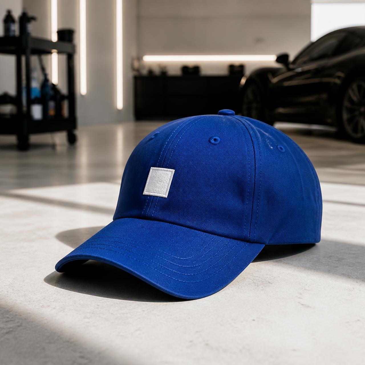A blue cap with an embroidered white chest badge